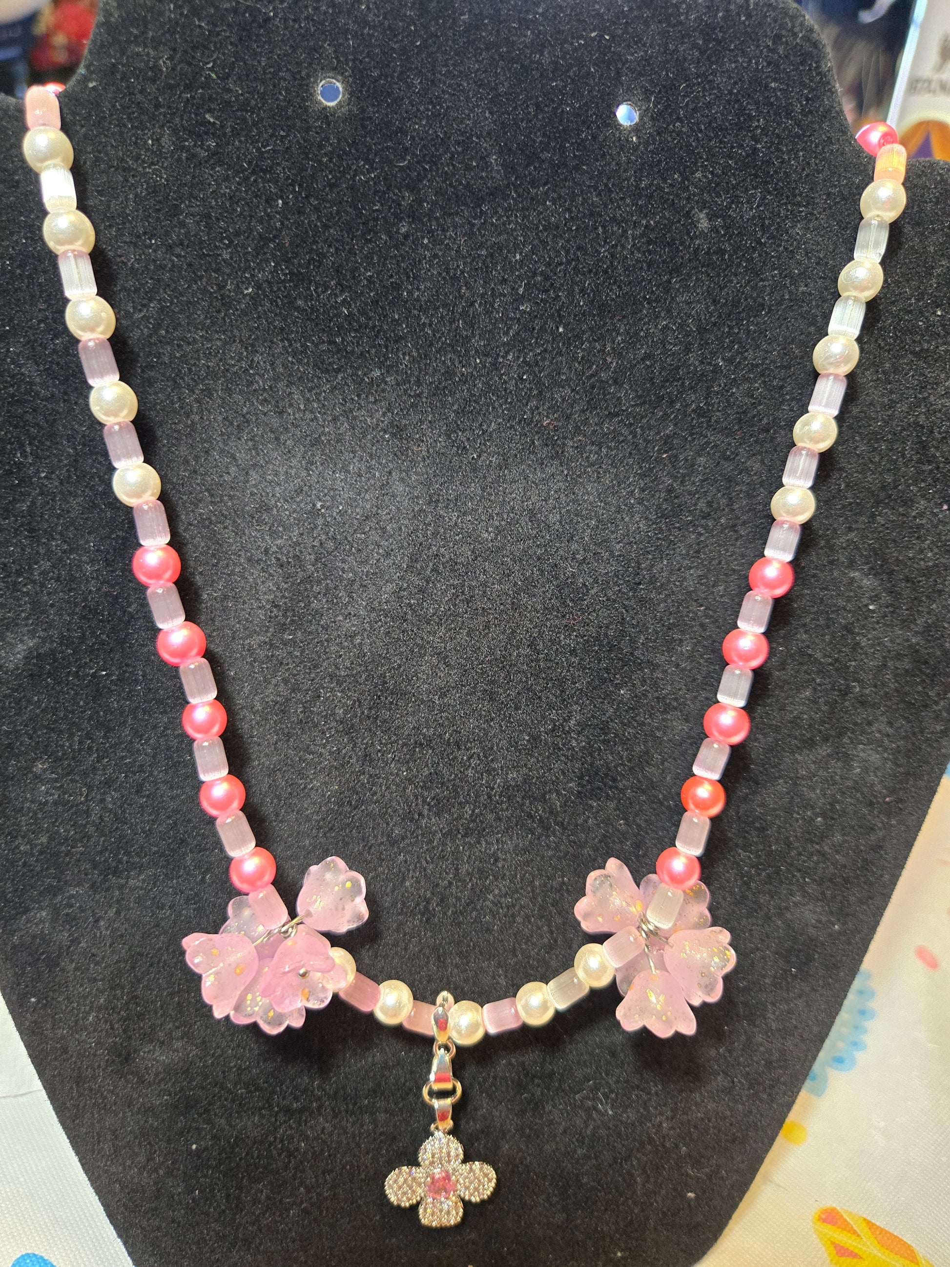 Pink and white beaded necklace with added floral beads and a pink and white gemstone pendant.