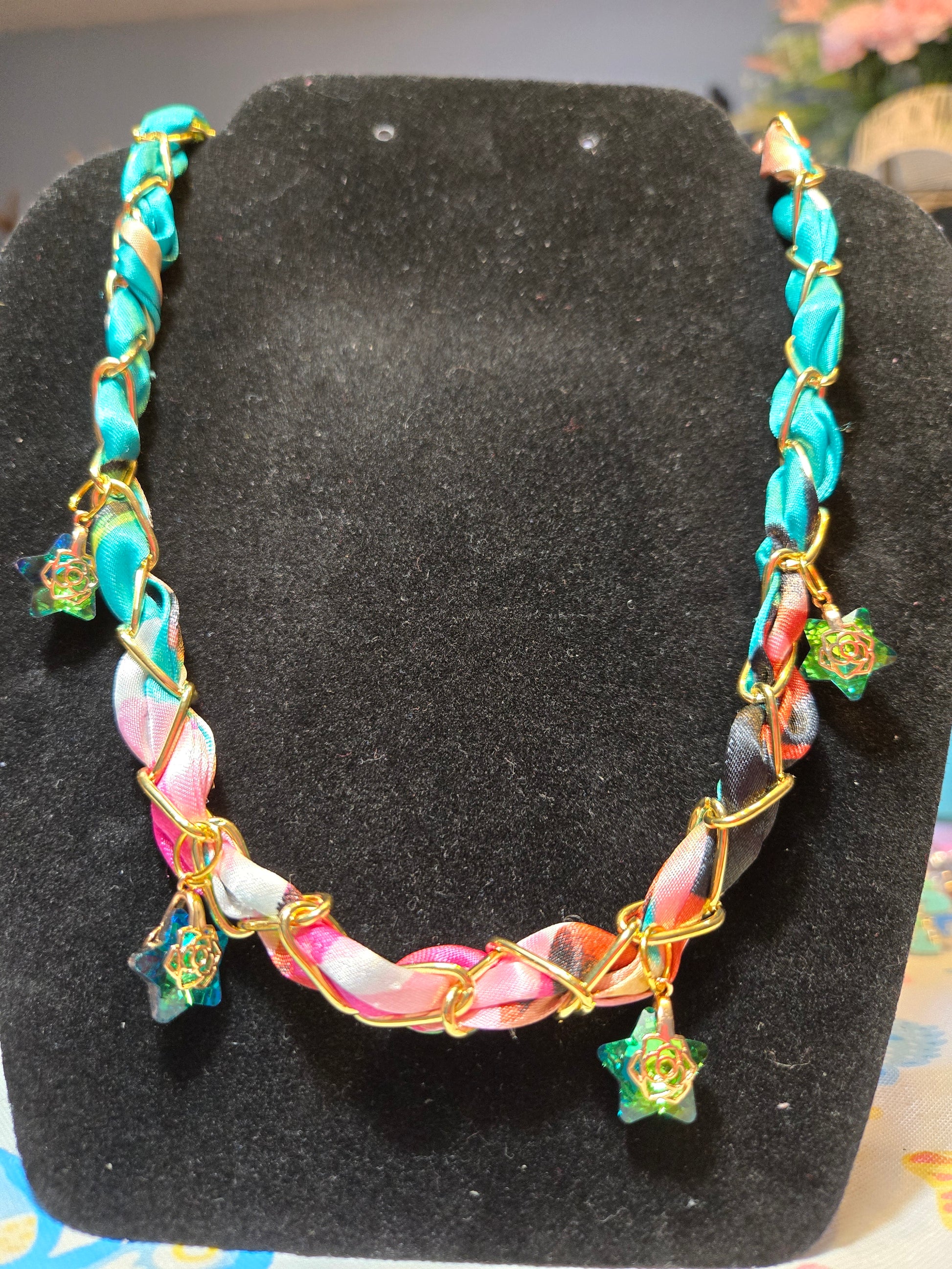 Colorful scarf braided in paperclip gold tone necklace.  Charms are green with gold accents. 