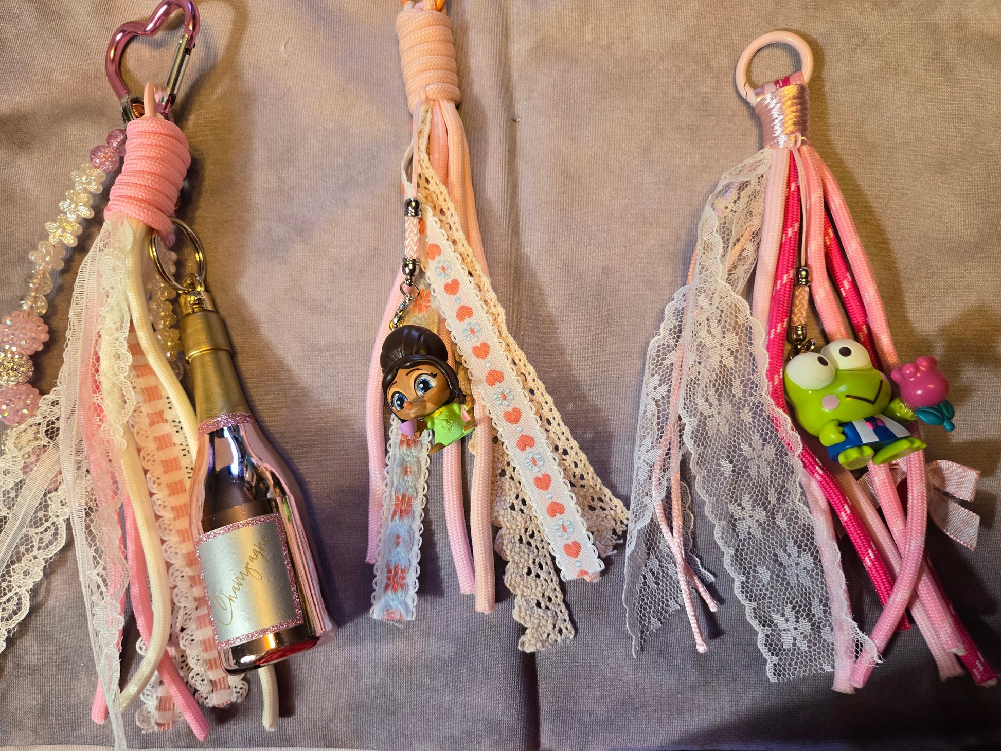 Three decorative keychains with lace, ribbons, and small figurines 